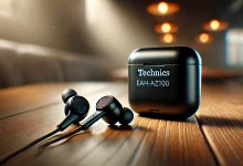 "A pair of sleek black Technics EAH-AZ100 earbuds placed next to their charging case on a wooden table, with soft lighting highlighting their premium design."